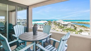 Ein Balkon mit Tisch, Stühlen, einer Vase und Blick auf Strand und Gebäude.