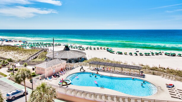Ein Resort mit Schwimmbad, Strandsonnenschirmen und Blick auf den Ozean.