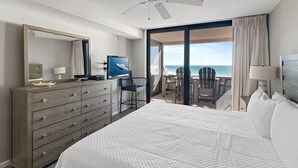 Ett hotellrum med en säng, en byrå, en tv och en balkong med utsikt över havet.