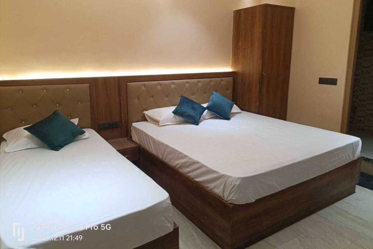 A hotel room with two beds, a wooden headboard, and a small bedside table.