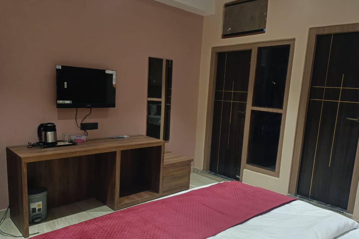 A room with a bed, a wooden desk, a television, and a wardrobe.