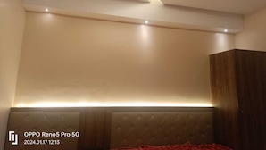 Une chambre à coucher moderne avec une tête de lit capitonnée, des spots encastrés au plafond et un ventilateur de plafond.