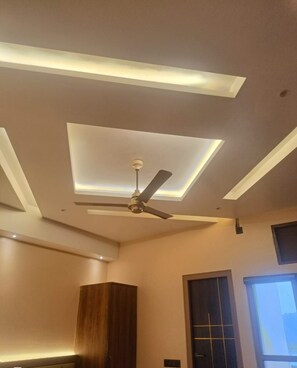 A modern room with a ceiling fan, recessed lighting, and a wooden cabinet. - MR JAISWAL DHARMSHALA (Sultanpur)