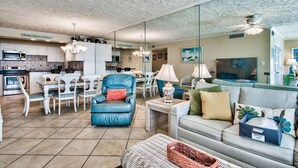 Ein geräumiges Wohnzimmer mit einem blauen Ledersofa, einem grauen Sofa und einem Essbereich mit weißen Stühlen.