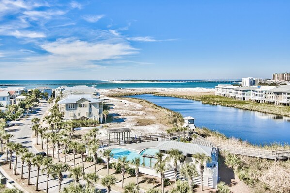 A coastal resort with a swimming pool, palm trees, and a view of the ocean.
