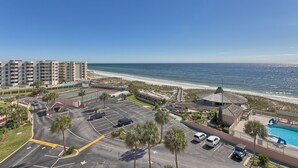 A beachfront hotel with a parking lot, a tennis court, and a pool area. - Fabulous sunset Jetty view! Enjoy one free beach chair setup each day! (Destin)