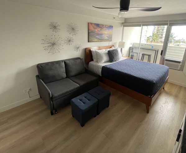 A modern bedroom with a bed, a sofa, and a small ottoman.