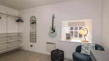Una habitación con una guitarra, un espejo, una lámpara y una silla.