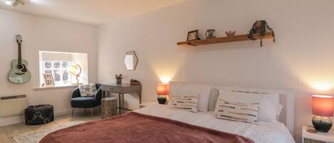 A bedroom with a bed, a desk, a chair, a guitar, and a window.