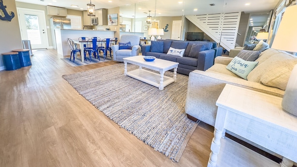 A modern living room with a sofa, coffee table, and a dining area with chairs and a table. - L👀K! NEW VRBO! Beach & Lake; Boat Ramp; Lake Powell! Rent both sides, sleeps 18 (Panama City Beach)