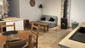 A cozy living area with a fireplace, a sofa, a dining table, and a kitchen area. - Gîte Charmant Dans Maison Ardéchoise au Coeur des Montagnes Pour Amoureux Nature (Saint-Michel-de-Chabrillanoux)