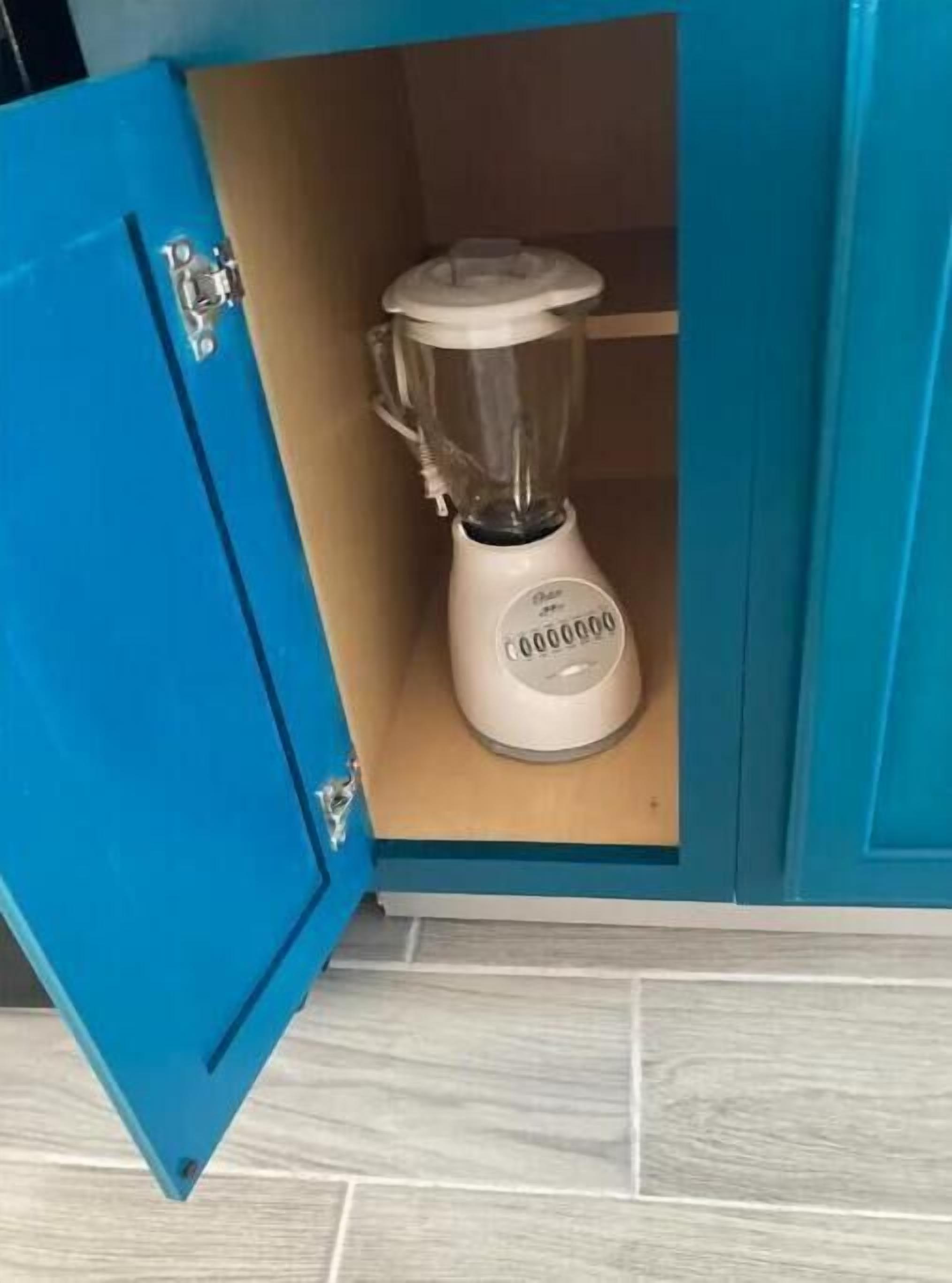 A kitchen with a blue cabinet containing a white blender.