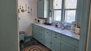 Una cucina con forno a microonde, tostapane e macchina del caff è sul piano di lavoro. Si vede una finestra con vista all'esterno.