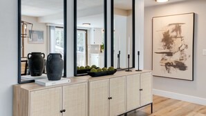 Een modern interieur met een grote spiegel, een kast met gevlochten deuren en een eigentijds schilderij.
