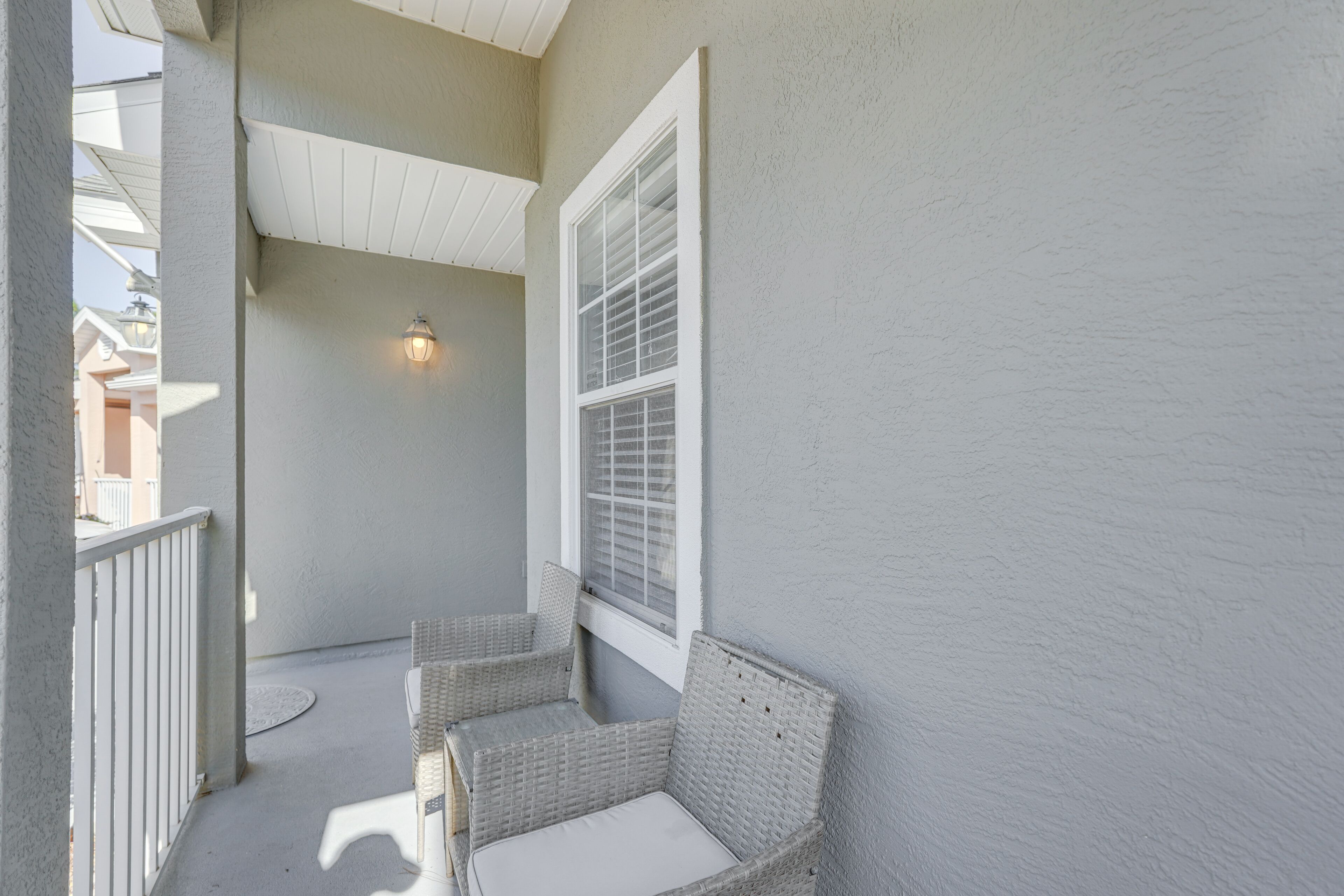 A balcony with wicker chairs and a window with blinds.