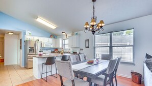 Een moderne keuken met witte kasten, een centraal eiland en een eethoek met een houten tafel en stoelen.