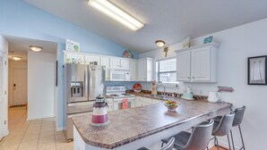 Een moderne keuken met witte kasten, een granieten aanrechtblad en een centraal eiland met barstoelen.