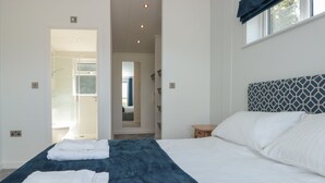 A bedroom with a large bed, a bedside table, and a window with a view. - Buttercup Lodge (Dartmouth)