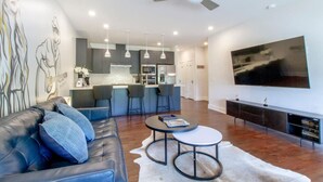 A modern living room with a leather sofa, a round coffee table, and a flat-screen TV mounted on the wall. - Prime Nashville Getaway – Peaceful Area (Nashville)