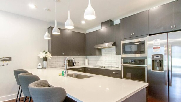 A modern kitchen with dark cabinets, a white countertop, stainless steel appliances, and pendant lighting. - Prime Nashville Getaway – Peaceful Area (Nashville)