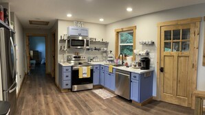 Una cocina moderna con suelo de madera, electrodomésticos de acero inoxidable y armarios azules.