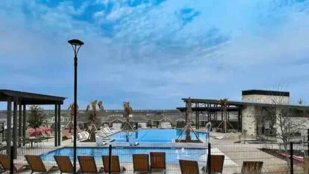 Un espace piscine avec des chaises longues, un coin salon abrité et un ciel dégagé.