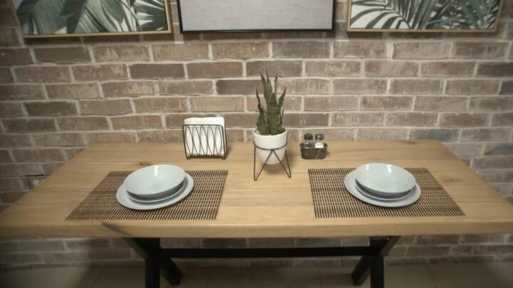 Een houten tafel met twee borden en een potplant.