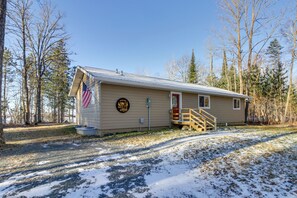 A small, single-story cabin with a red door and a wooden staircase leading to the entrance. - Hines Vacation Rental w/ Grill: Walk to Lake! (Hines)