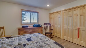 Une chambre à coucher avec un grand lit, une commode en bois, un fauteuil à bascule et une armoire aux portes en bois.