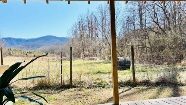 Een jacuzzi onder een houten pergola met uitzicht op een grasveld en bergen op de achtergrond.