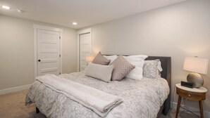 A bedroom with a bed, bedside tables, and a door. - Cozy, Quiet East Bench Basement Apartment  (Sandy)