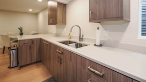 A modern kitchen with wooden cabinets, a stainless steel sink, and a countertop. - Cozy, Quiet East Bench Basement Apartment  (Sandy)