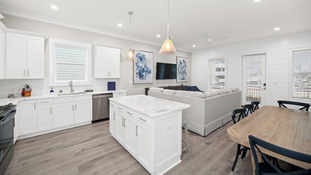 A modern kitchen with white cabinetry, a central island, and pendant lighting.