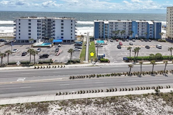 A hotel with multiple floors, a parking lot, and a view of the ocean.