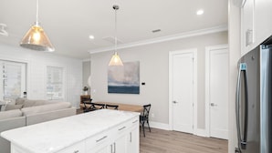 A modern kitchen with white cabinetry, a marble countertop, and a stainless steel refrigerator.