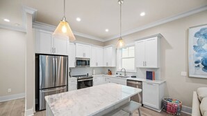 A modern kitchen with white cabinets, stainless steel appliances, and a marble island.