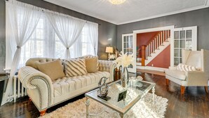 Ein Wohnzimmer mit einem beigefarbenen Sofa, einem Glastisch und einer Treppe im Hintergrund.