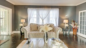 Ein Wohnzimmer mit einem beigefarbenen Sofa, einem Glastisch und einem Kronleuchter.