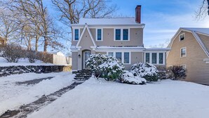 Ein zweistöckiges Haus mit verschneitem Einfahrt und umliegendem Strauchwerk.
