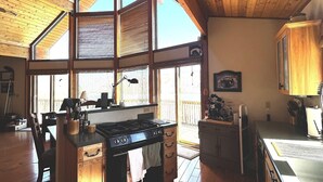 Una cocina amplia con pisos de madera, una isla grande con estufa y vistas a través de ventanales.