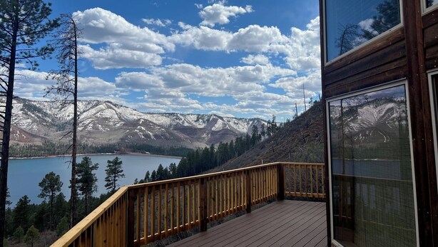 Una terraza de madera con vistas a montañas nevadas y un lago.