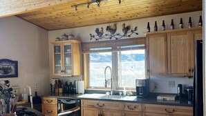 Una cocina rústica con armarios de madera, estufa empotrada y ventana con vistas al exterior.