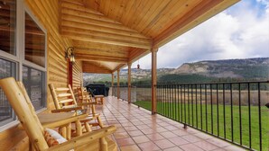 Eine Holzterrasse mit Sitzgelegenheiten und Blick auf eine gebirgige Landschaft.