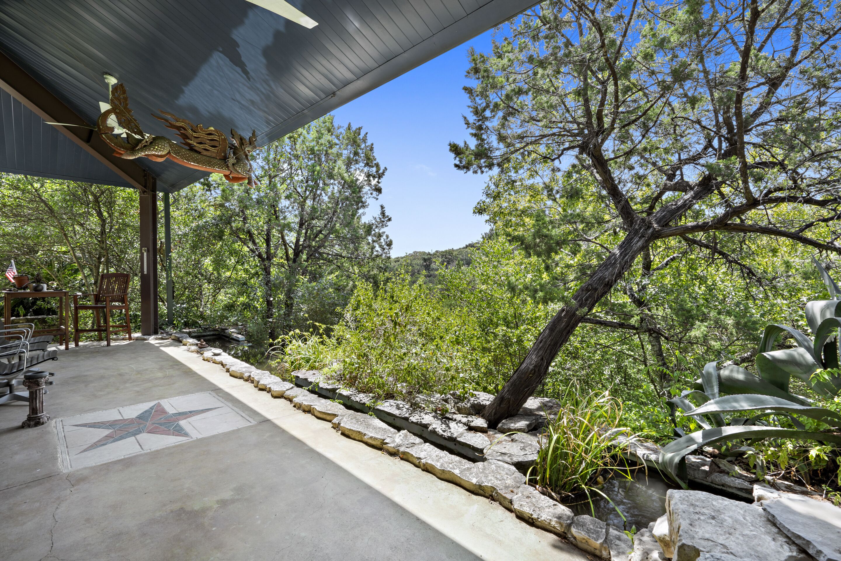 A covered outdoor area with a star-patterned floor, stone pathway, and a decorative dragon sculpture.