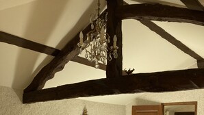 Een slaapkamer met een houten bed, een houten dressoir, een stoel, een kroonluchter en een deur die uitkomt op een balkon.