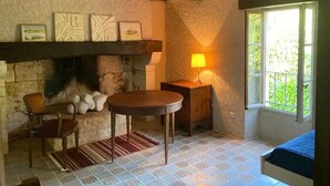 Een gezellige kamer met een stenen openhaard, een houten tafel en een comfortabele stoel.