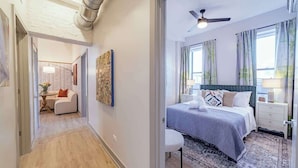 Een moderne hotelkamer met een groot bed, een plafondventilator en uitzicht op de stad.