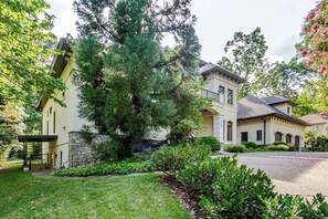 A two-story building with a stone facade, a large tree in front, and a well-maintained lawn.