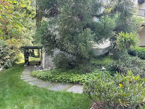 Un jardín con un sendero de piedra que lleva a un porche cubierto.