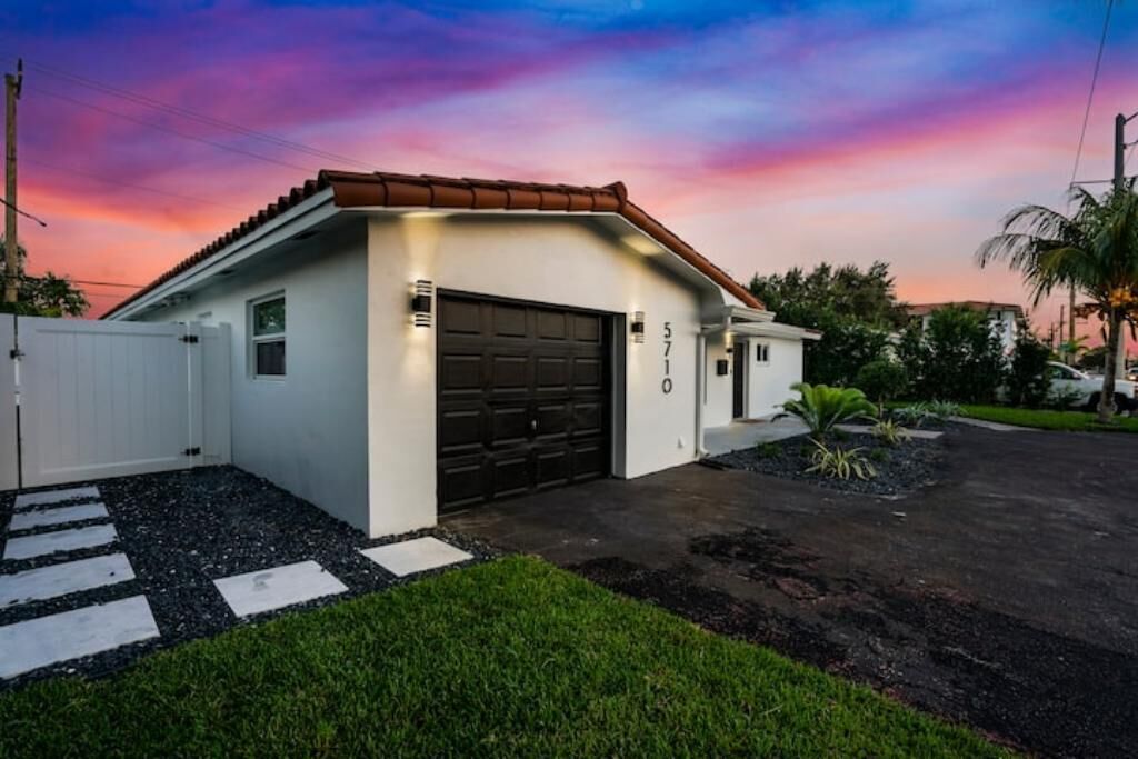 A modern single-story house with a garage, a well-maintained lawn, and a driveway leading to the garage.